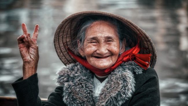 portrait einer älteren asiatisch stämmigen frau mit hut, lächelnd